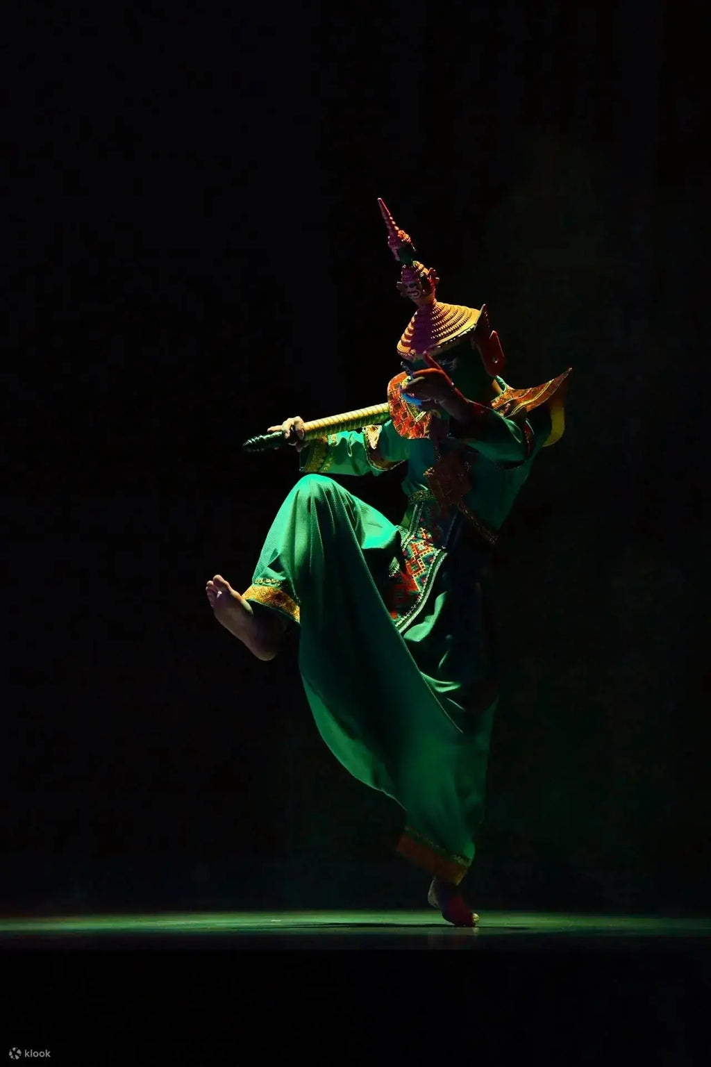 Dancer in colorful costume performing on a dark stage